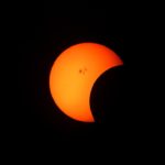 sun passing over a red moon in a solar eclipse